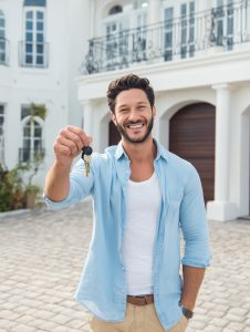 A man showing keys to a luxury mansion